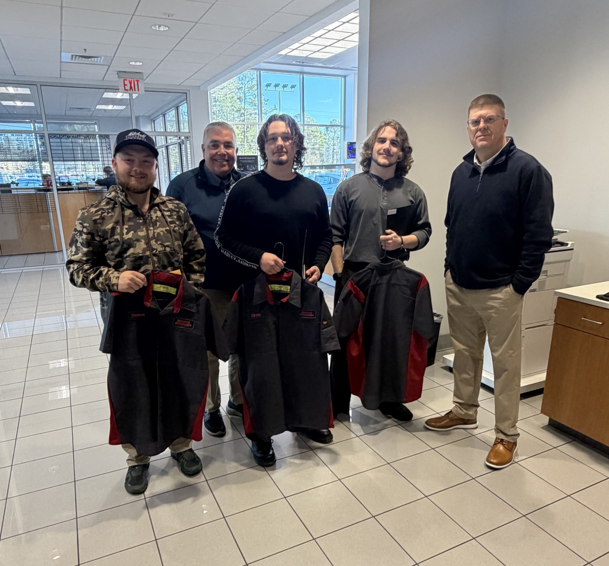 Jason Brunson with UniFirst presents custom technician shirts to Geneva County Automotive Tech students at Mitchell Nissan