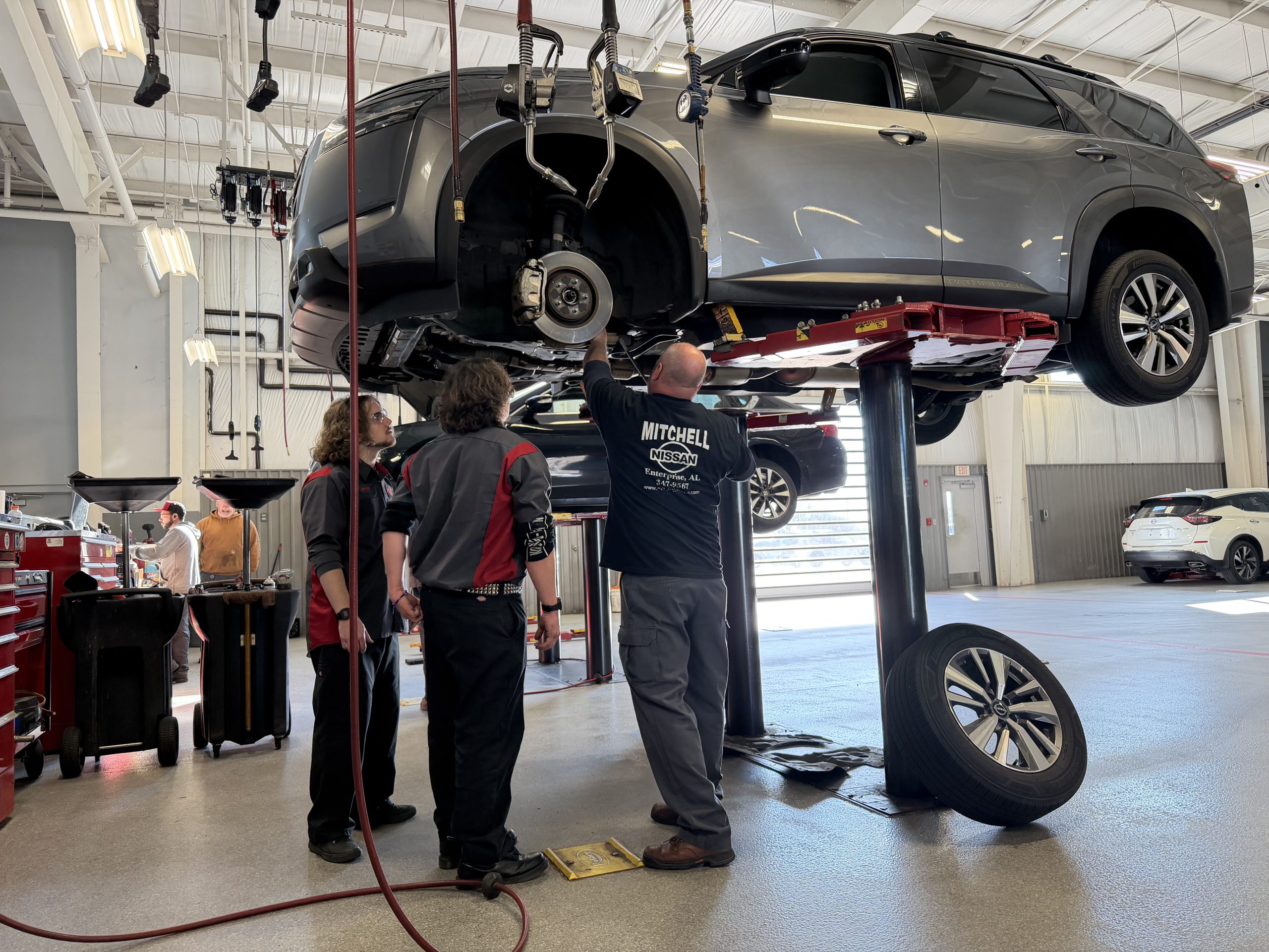 Students observe Mitchell Nissan Shop Foreman Darrell Zinn as he works on a vehicle in the service shop.