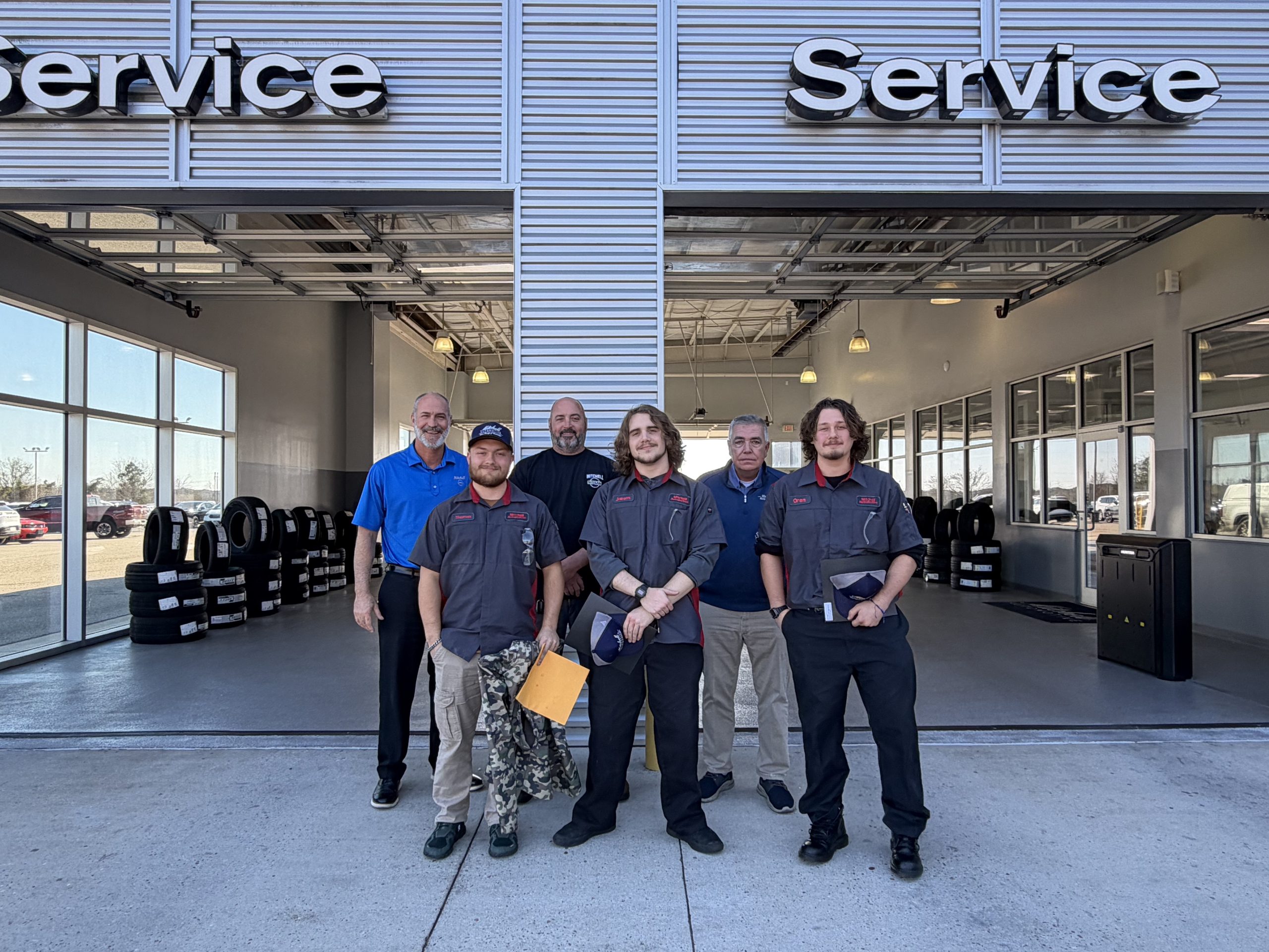 Three Geneva County Automotive Tech students pose with James Snider (Service Manager), Darrell Zinn (Shop Foreman), and Bob Schoenfeld (Fixed Operations Manager) at Mitchell Nissan